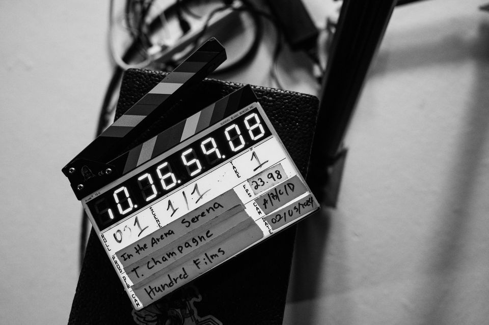 Clapperboard with digital time display, indicating the start of the shot, placed on a surface with some cables in the background.