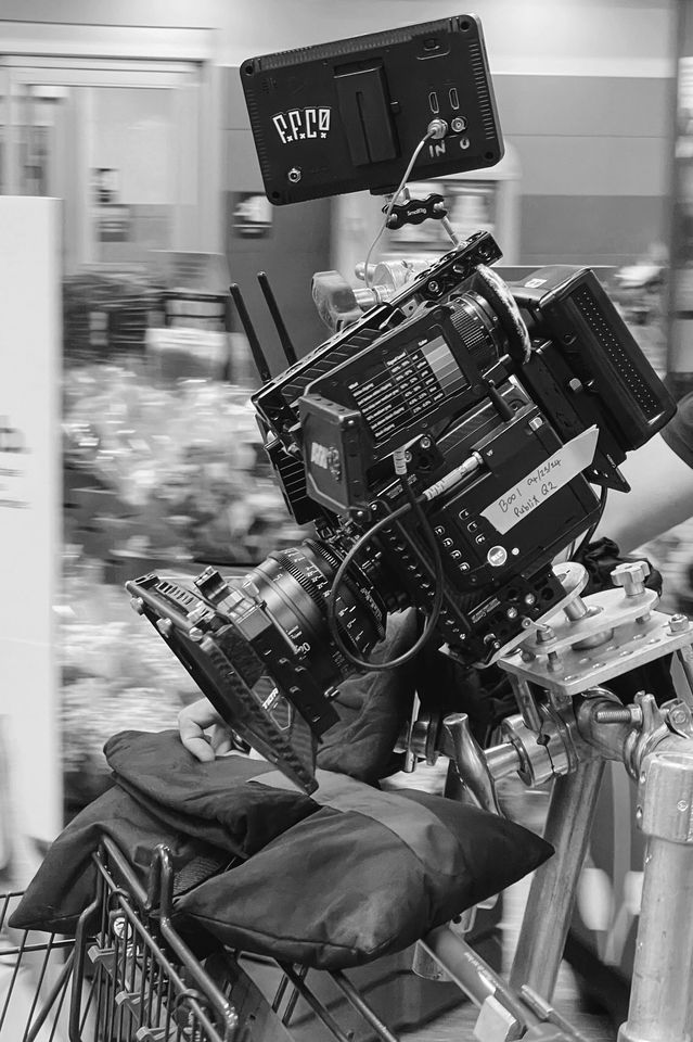 A professional camera setup mounted on a bicycle with a padded seat, equipped with multiple electronic devices and accessories in a retail store setting.