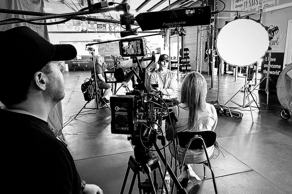 Filming a video interview with two people inside a studio with professional lighting and camera equipment.