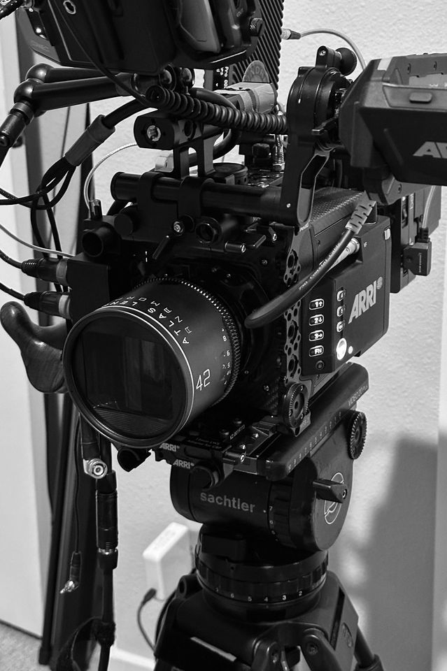 Black and white photo of a professional cinema camera mounted on a tripod.